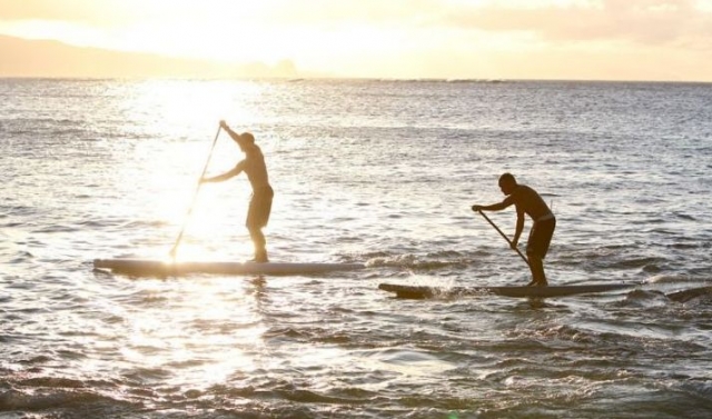 两个男孩在日落时练习桨冲浪